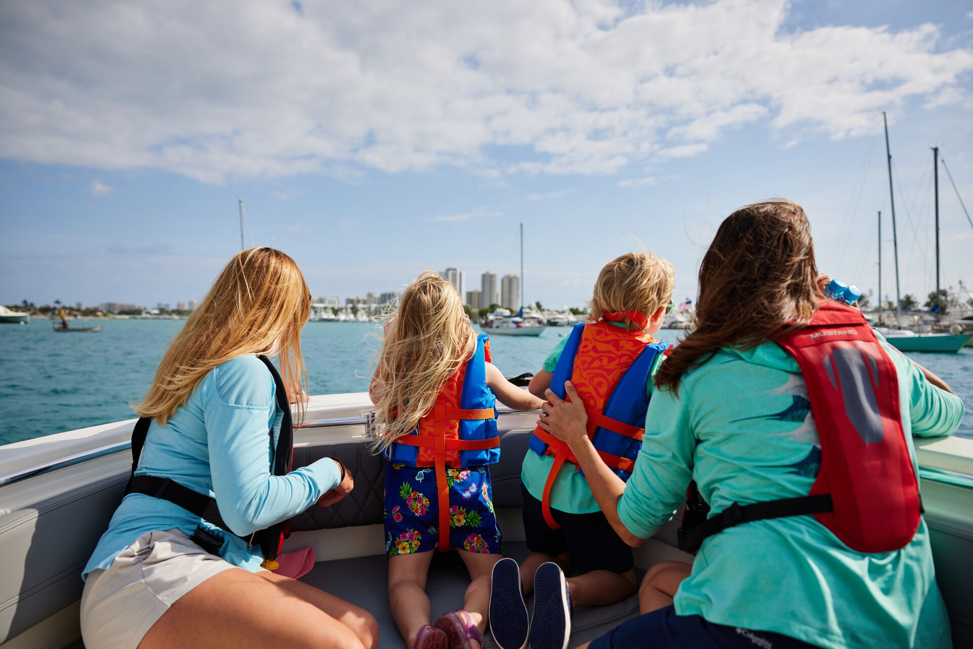 Two kids and two women wear life jackets on boat, life jacket laws by state concept. 