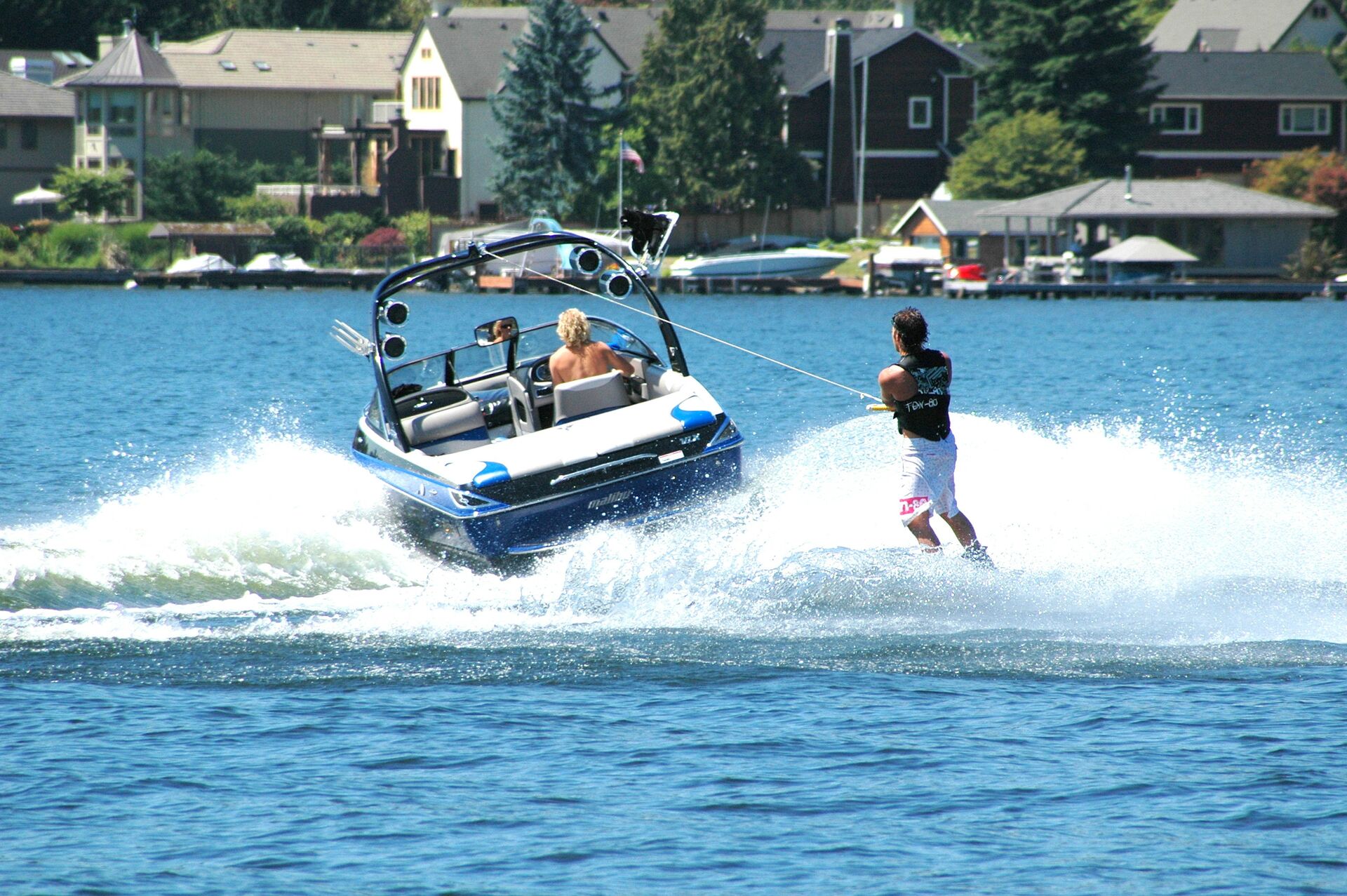Boat pulls a guy on a water ski on a lake.
