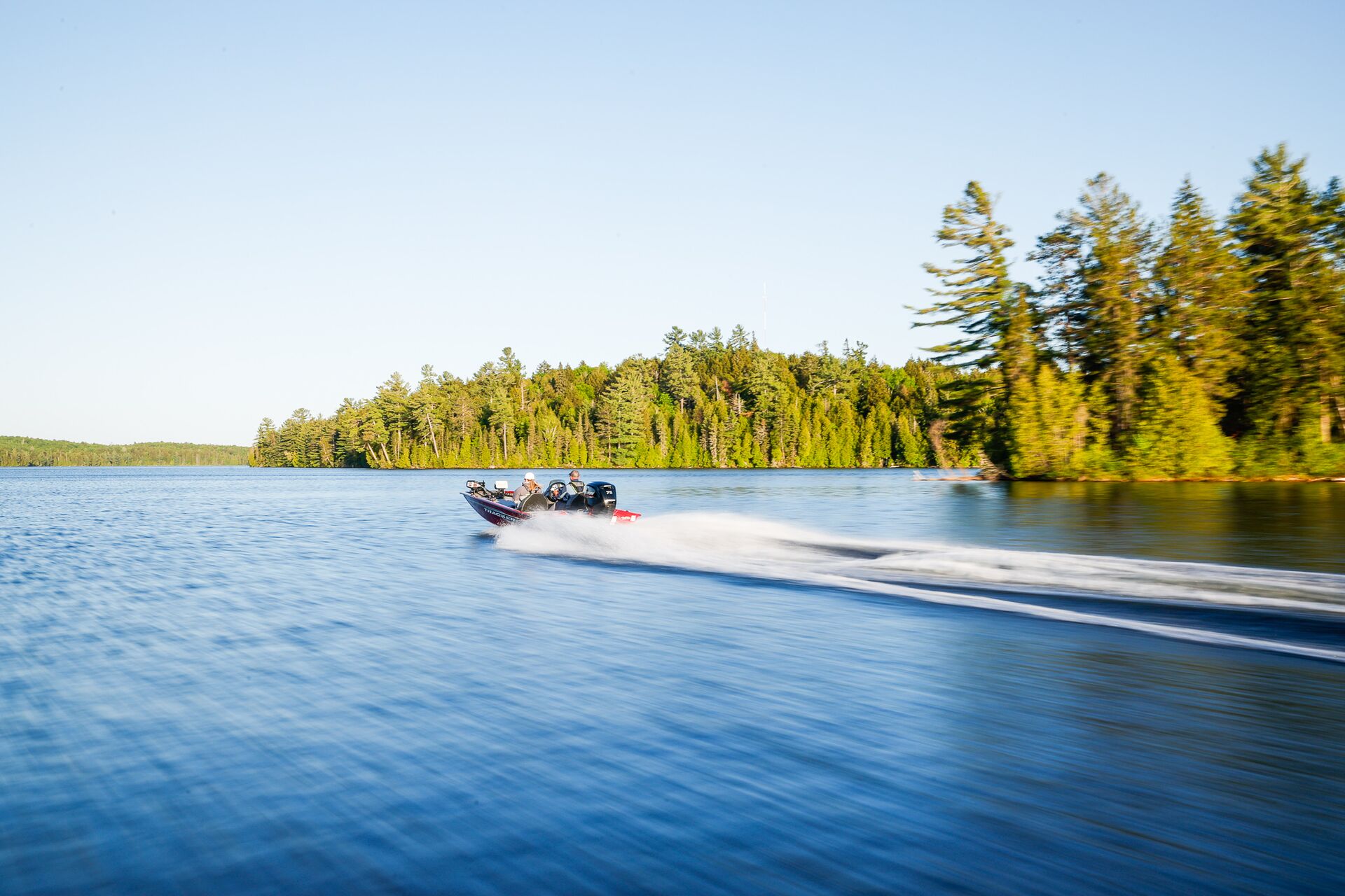 Fishing boat moves across lake with trees on shore, best boating lakes concept. 