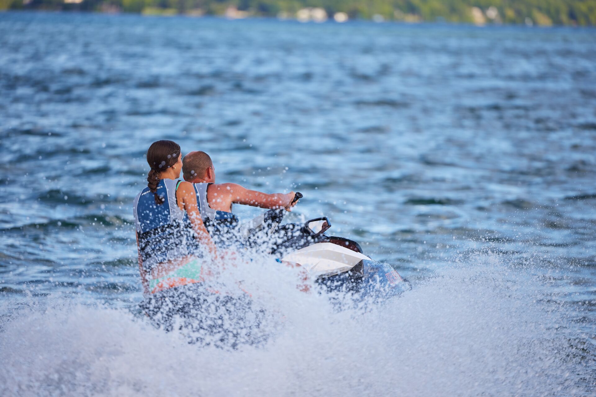 Man and girl ride away on a jet ski.