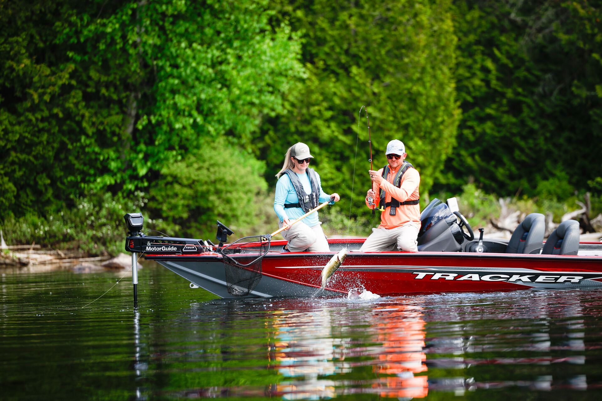 Man and woman fishing from red bass boat on a lake. 