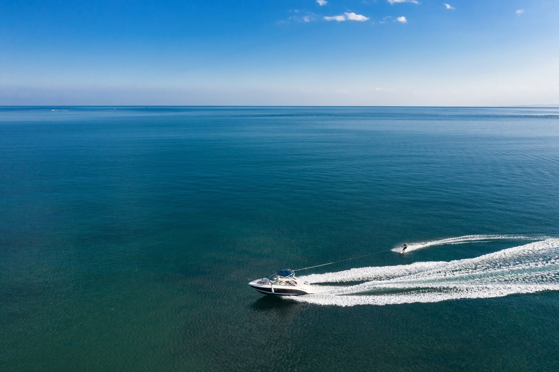 Wide view of a boat pulling a waterskier, check the weather on water before boating concept.