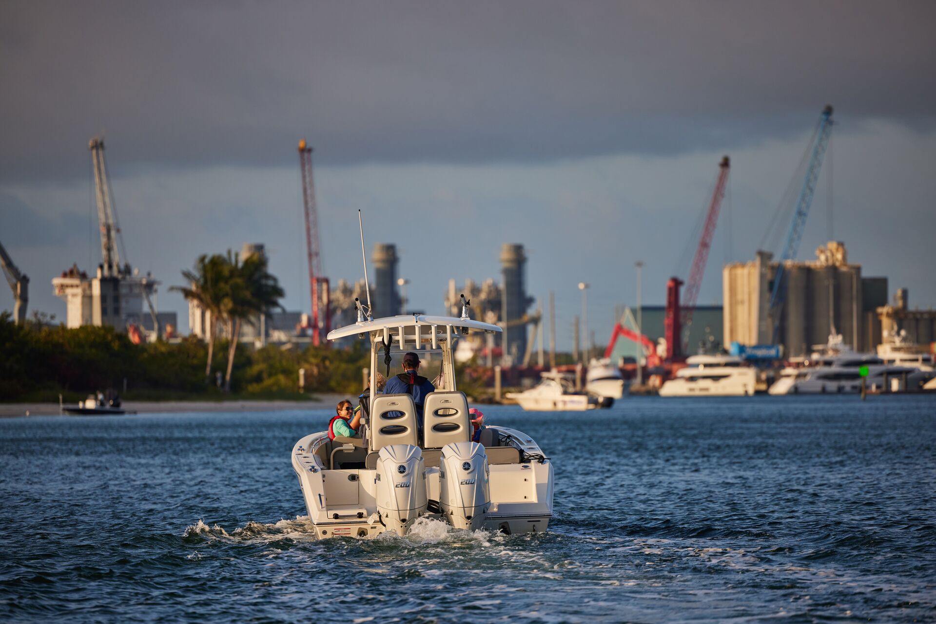 A boat with people on board on the water with a dark cloud overhead.