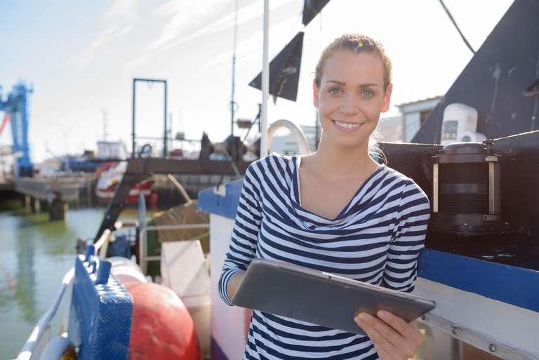 A woman smiles and holds a clipboard on a boat, what is a float plan concept. 