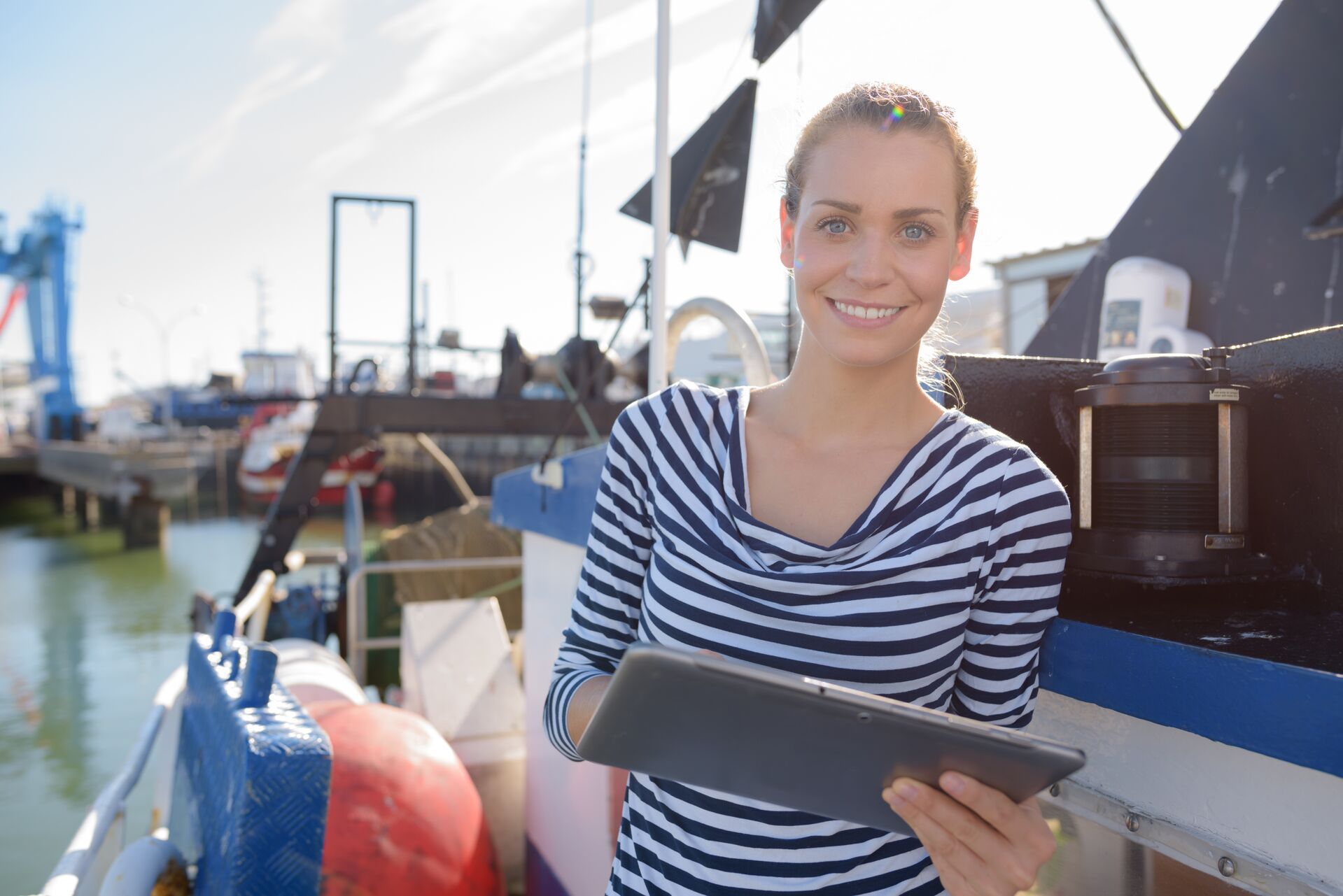 A woman smiles and holds a clipboard on a boat, what is a float plan concept. 