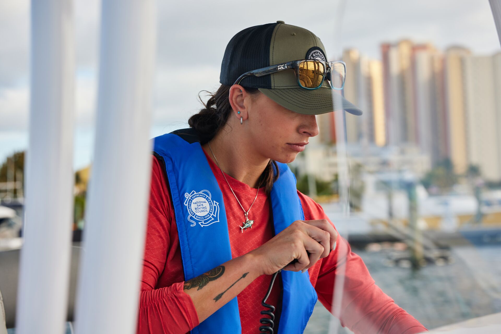 A woman uses a radio on a boat, wearing a life jacket. 