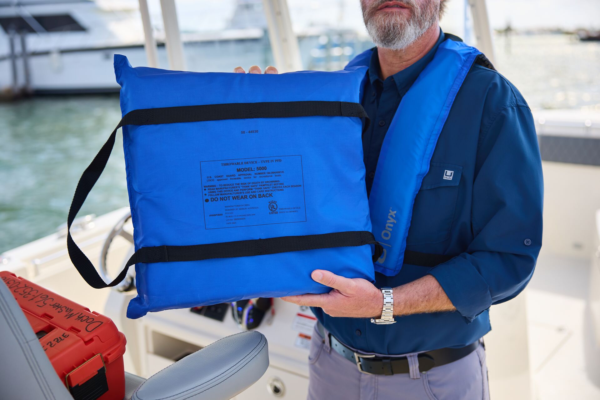 A man on a boat holds a throwable device used to render aid.