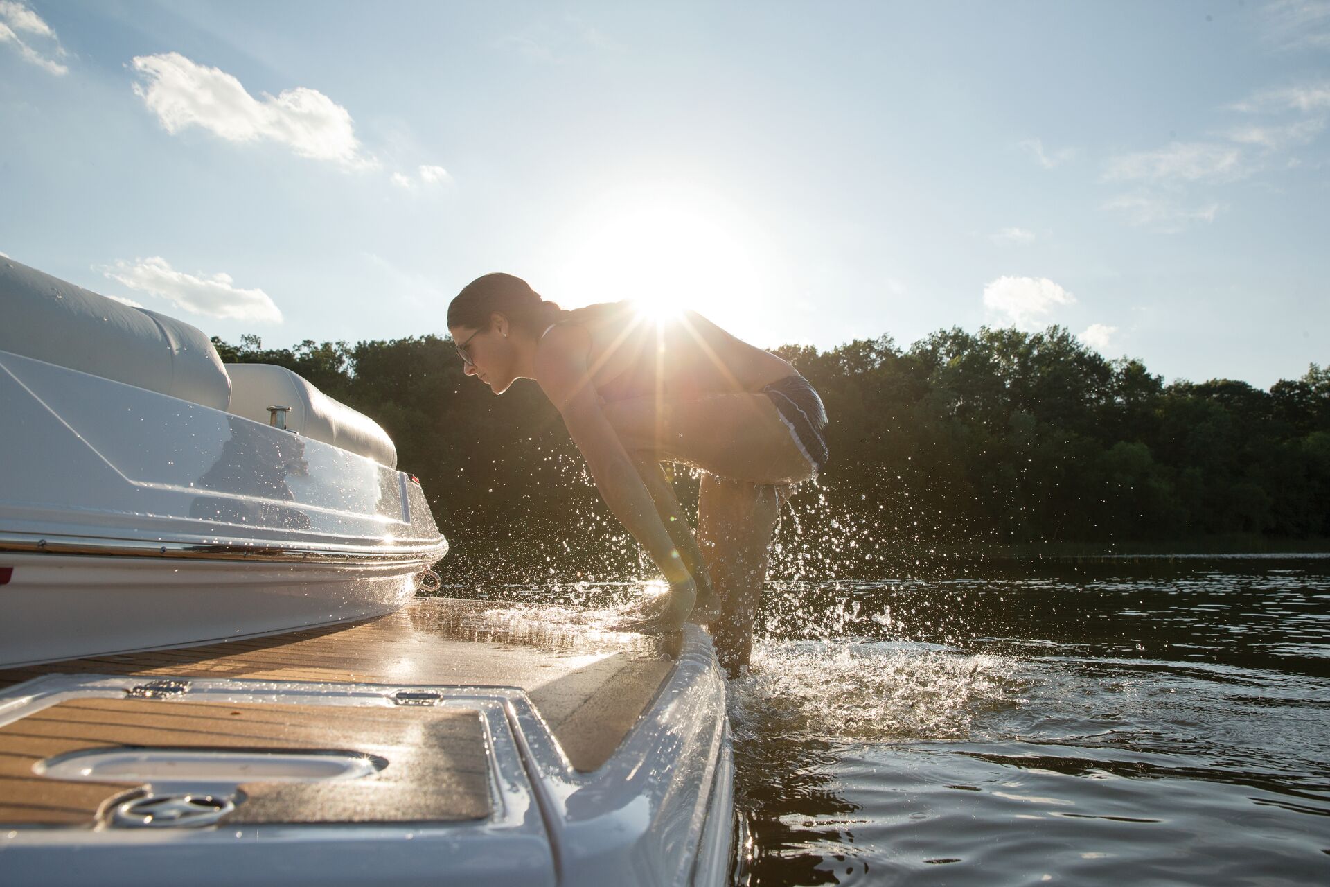A girl getting out of the water onto a boat, what to do if someone falls overboard concept.