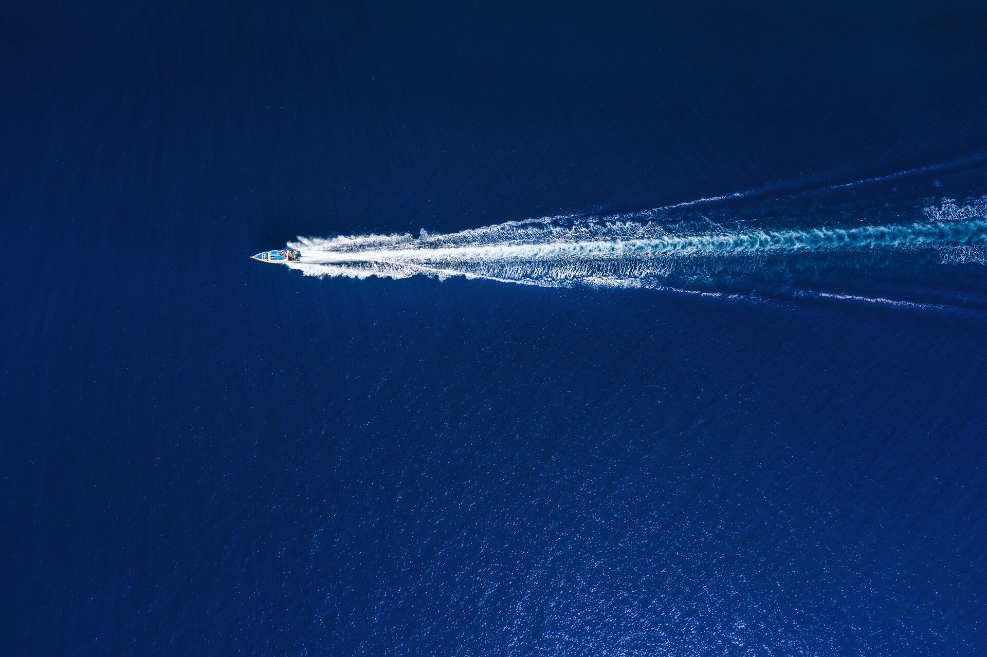 Overhead view of a boat creating a wake on the water.