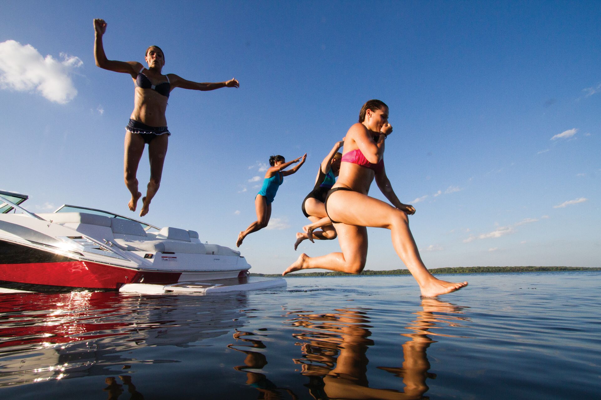 Several people jumping from a boat into the water, when is a written boating accident required concept.