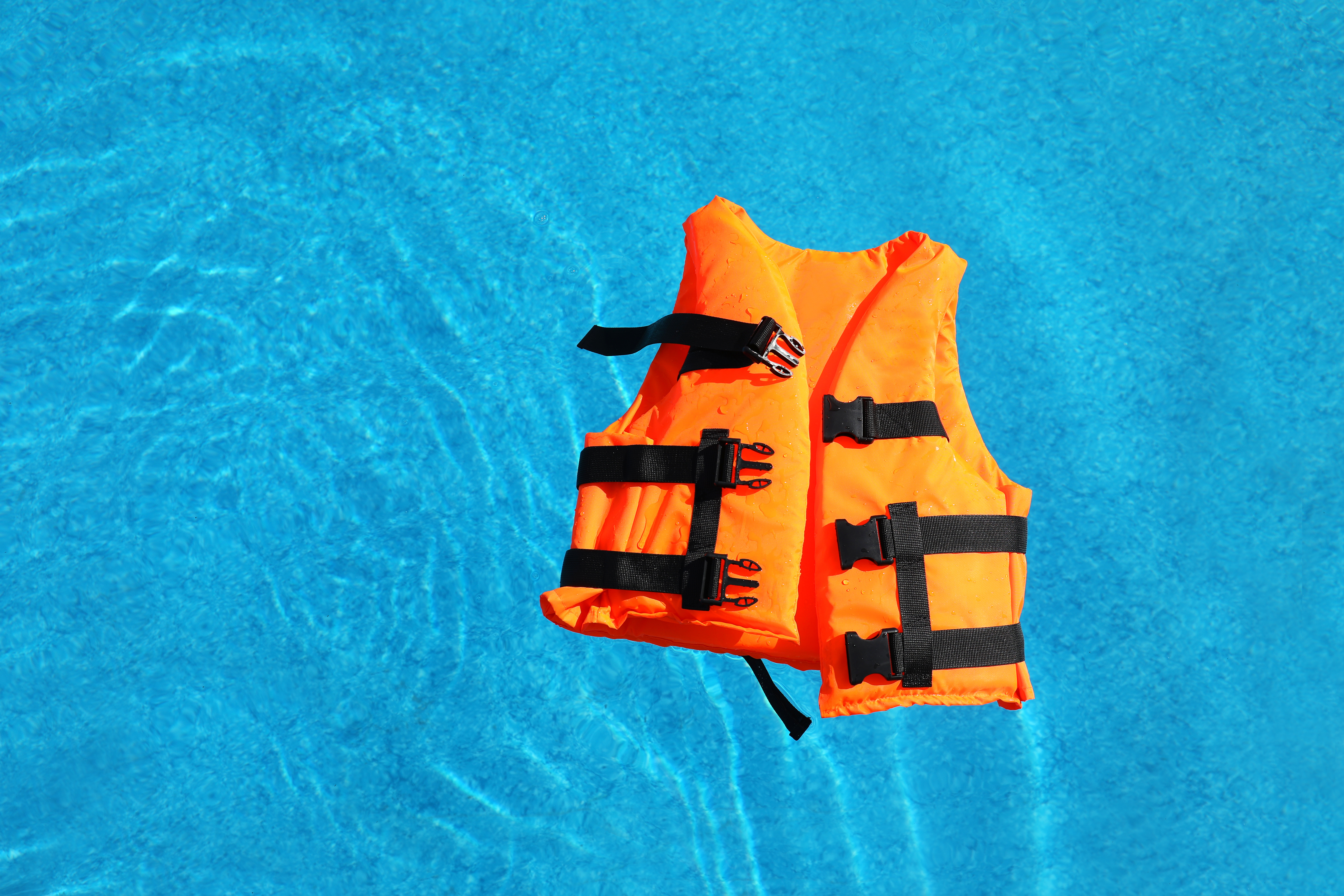 A life jacket floats on water, boater safety concept.