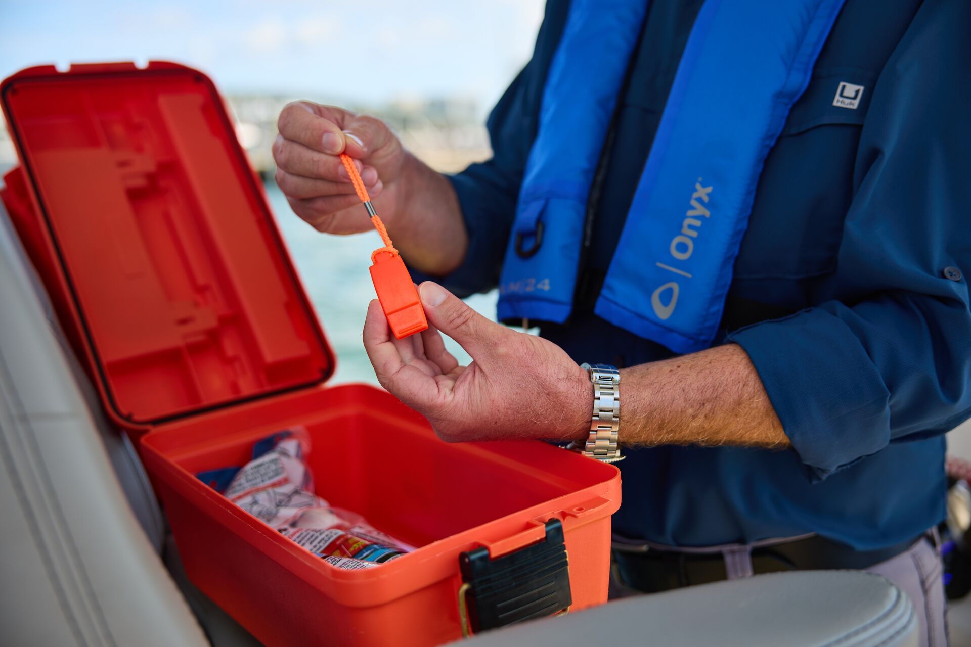 A man holds a whistle, safety equipment on a boat concept.