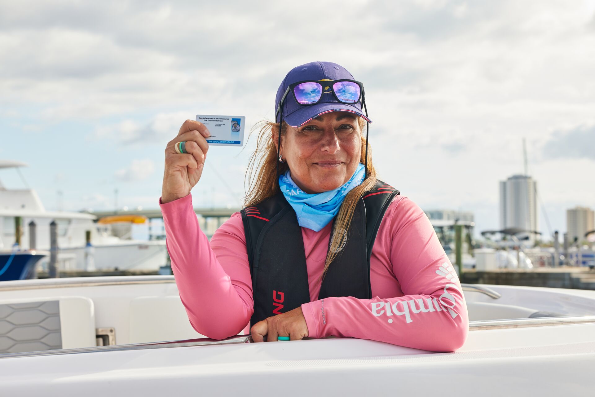 A woman smiles and holds up a boating license, out of state boating license concept.