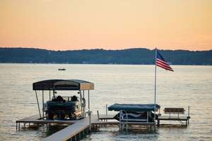 A boat at a dock flying the U.S. flag on a lake.