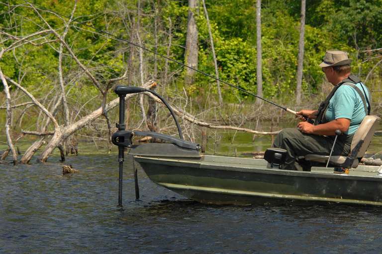 A man fishing in an aluminum fishing boat.