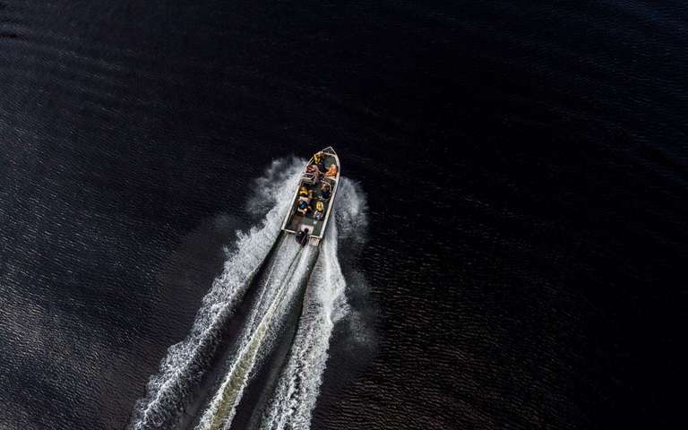 Overhead view of a small boat with passengers moving on the water, Oregon boating regulations concept. 