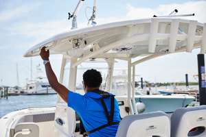 Back view of a man wearing a life vest driving a boat, California boating laws concept.