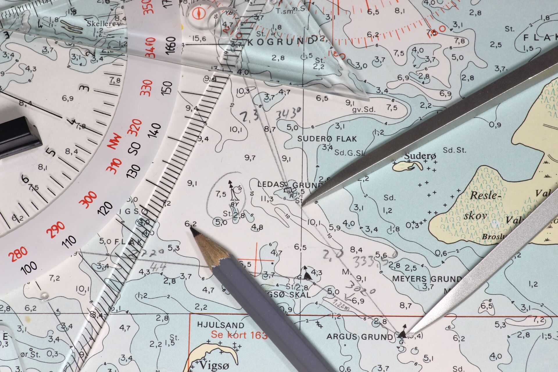 Pencils and tools on a nautical chart to plot a course.