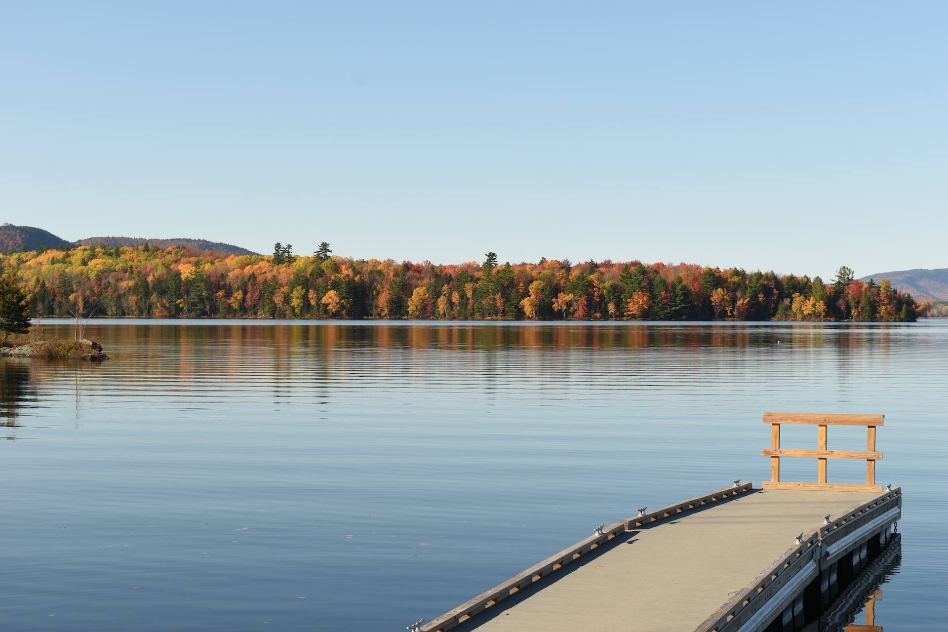 A dock on a lake surrounded trees with changing leaves, Umbagog lake boat launch concept. 