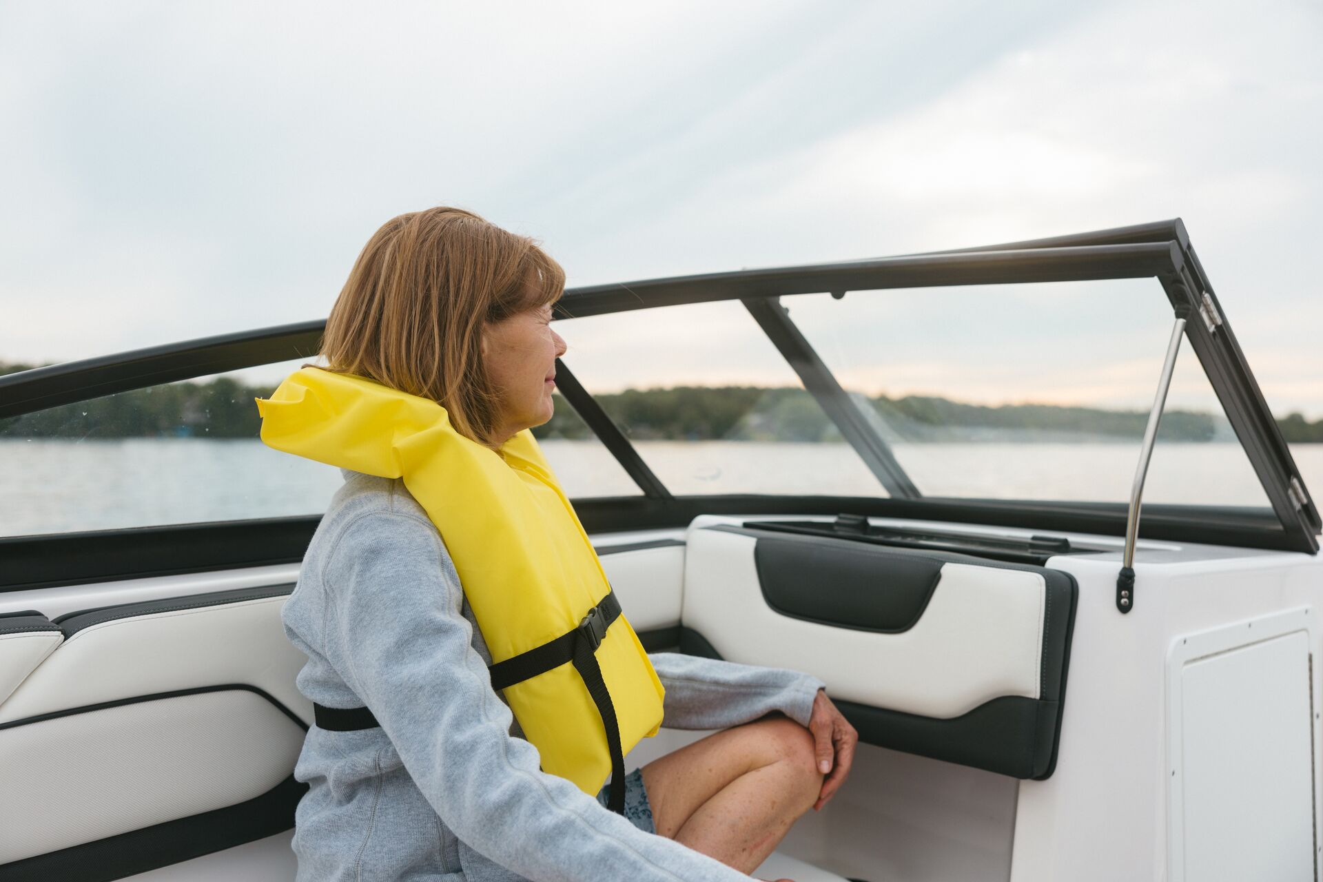 A woman wears a yellow life jacket on a boat.