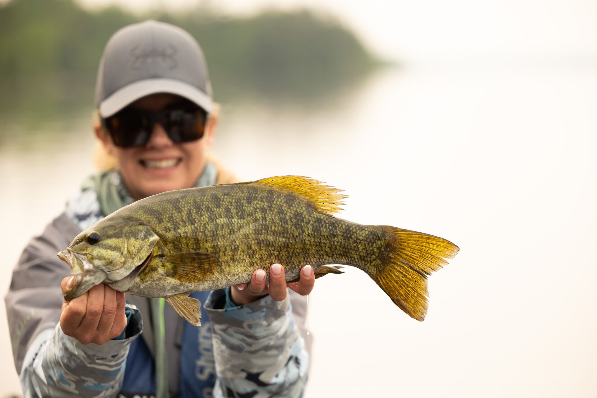 Close-up of woman holding a fish while on the water.