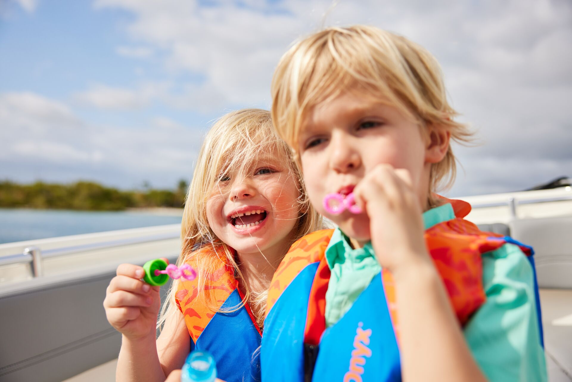 Two kids wear life jackets on a boat and blow bubbles, National Safe Boating Week concept. 