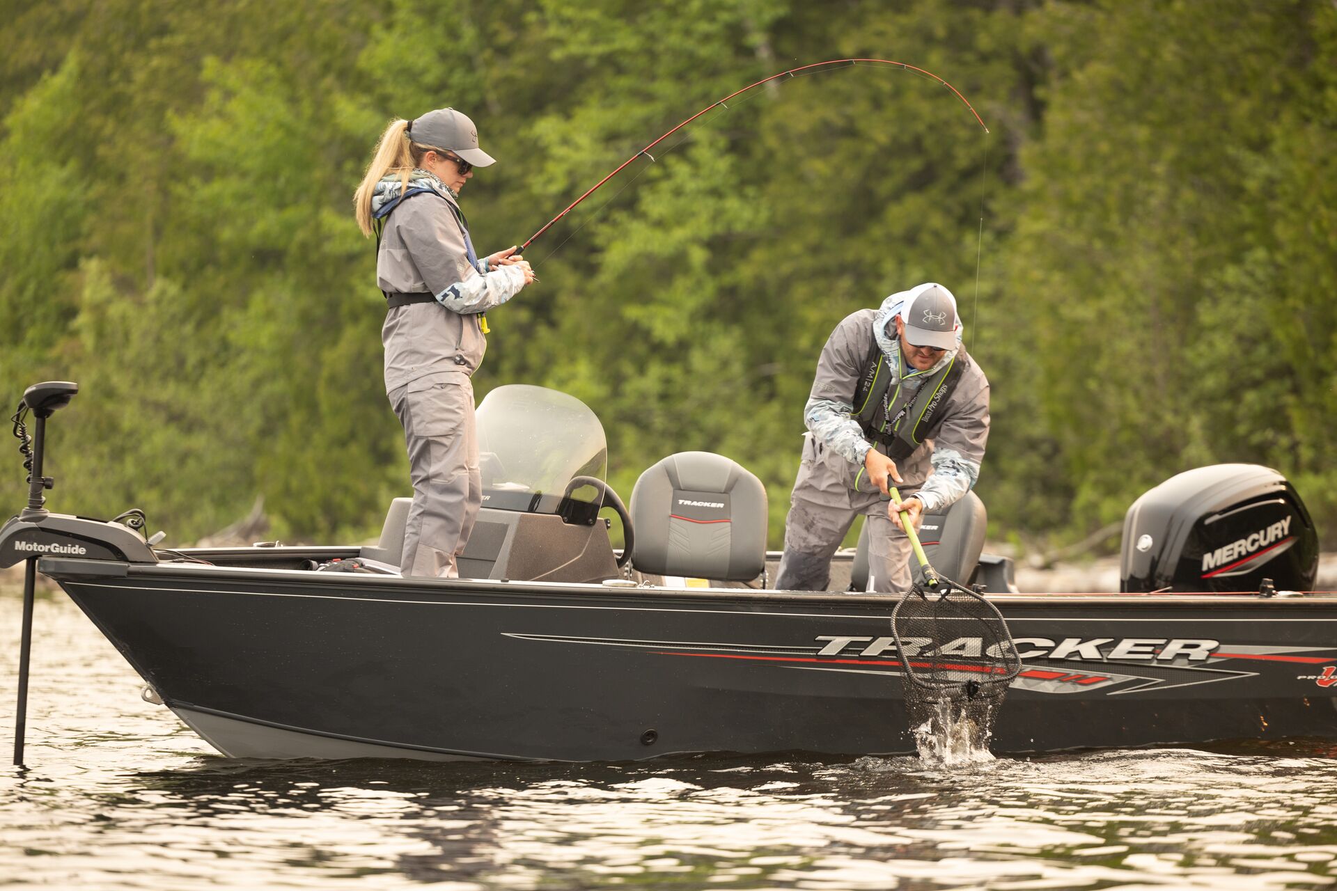 Woman and man pulling a fish onto a boat, represents National Fishing and Boating Week.