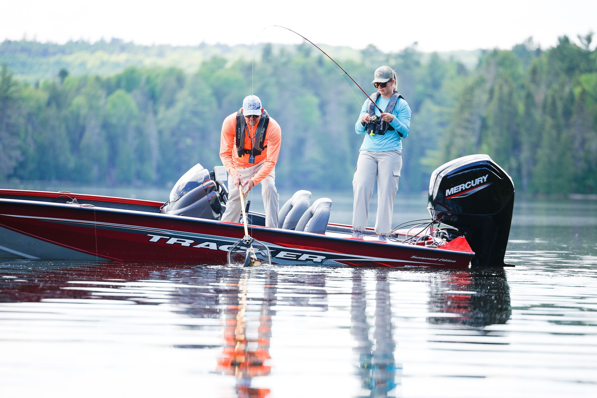 Man and woman on boat reel in fish, fishing boat etiquette concept. 