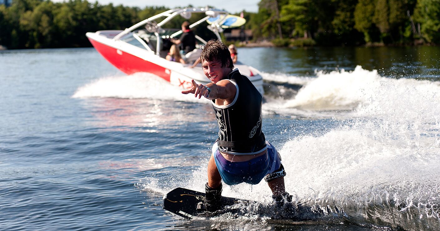 Guy on a wakeboard behind a boat, boat towing on water safety concept.