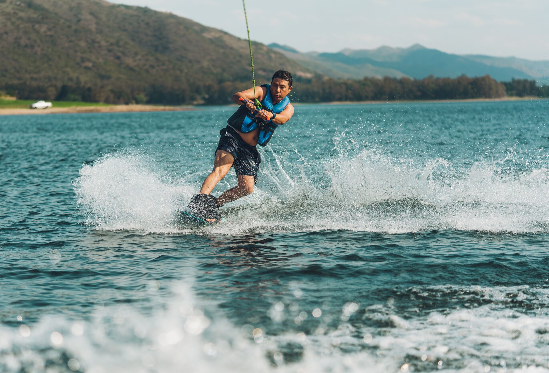 Guy holding rope to wakeboard, staying safe when boat towing on water concept. 