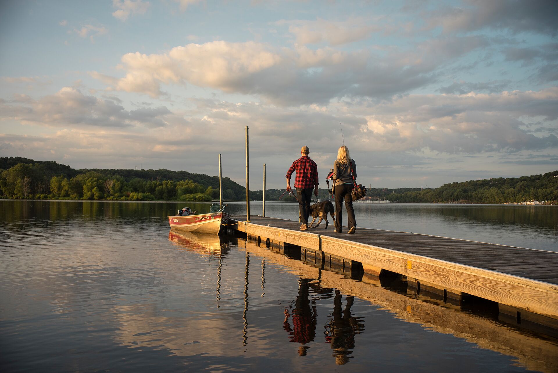 People with a dog on a dock, lifejacket for dogs when boating concept. 