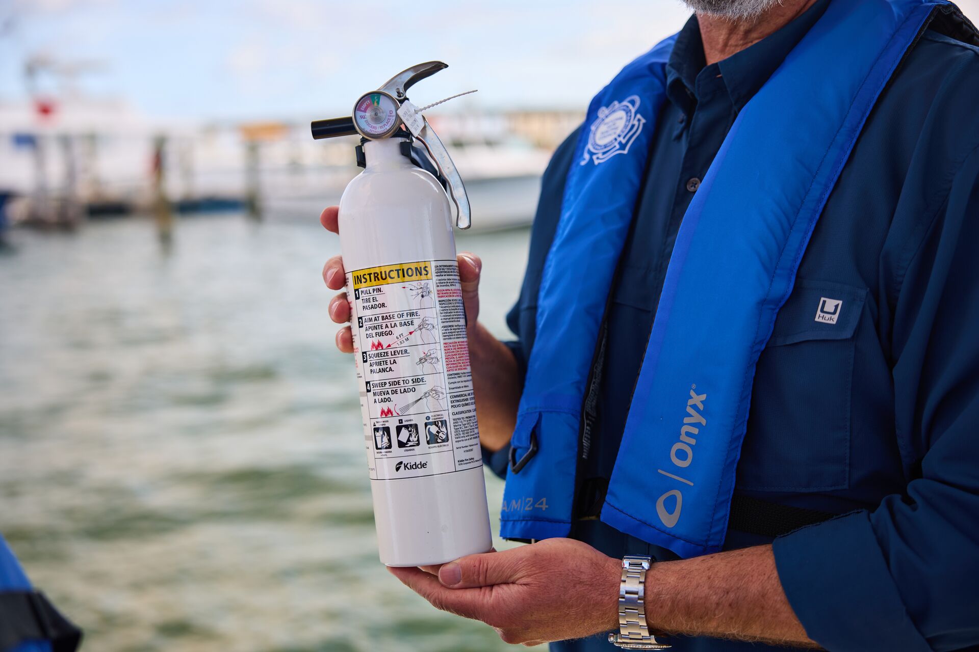 Man holding boat fire extinguisher, where should a fire extinguisher be stored on a boat concept. 