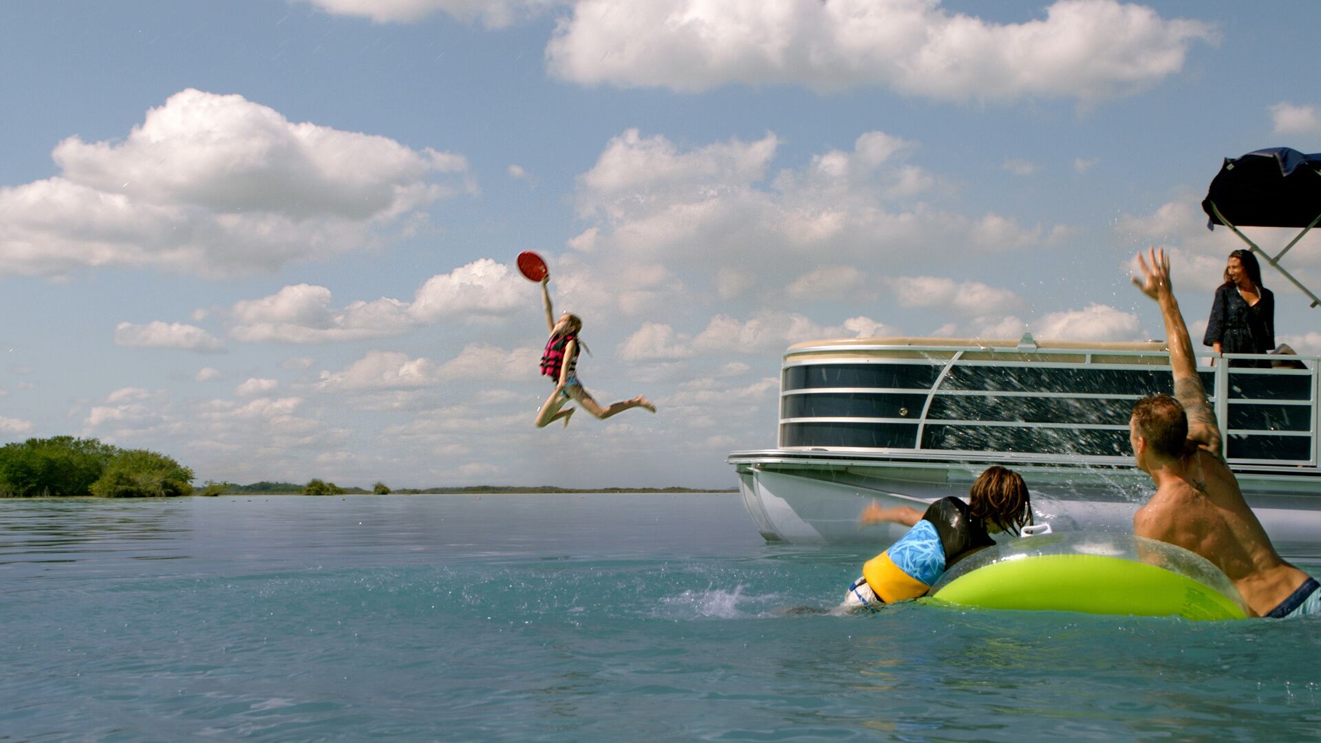 Girl jumps from boat near people in water. 
