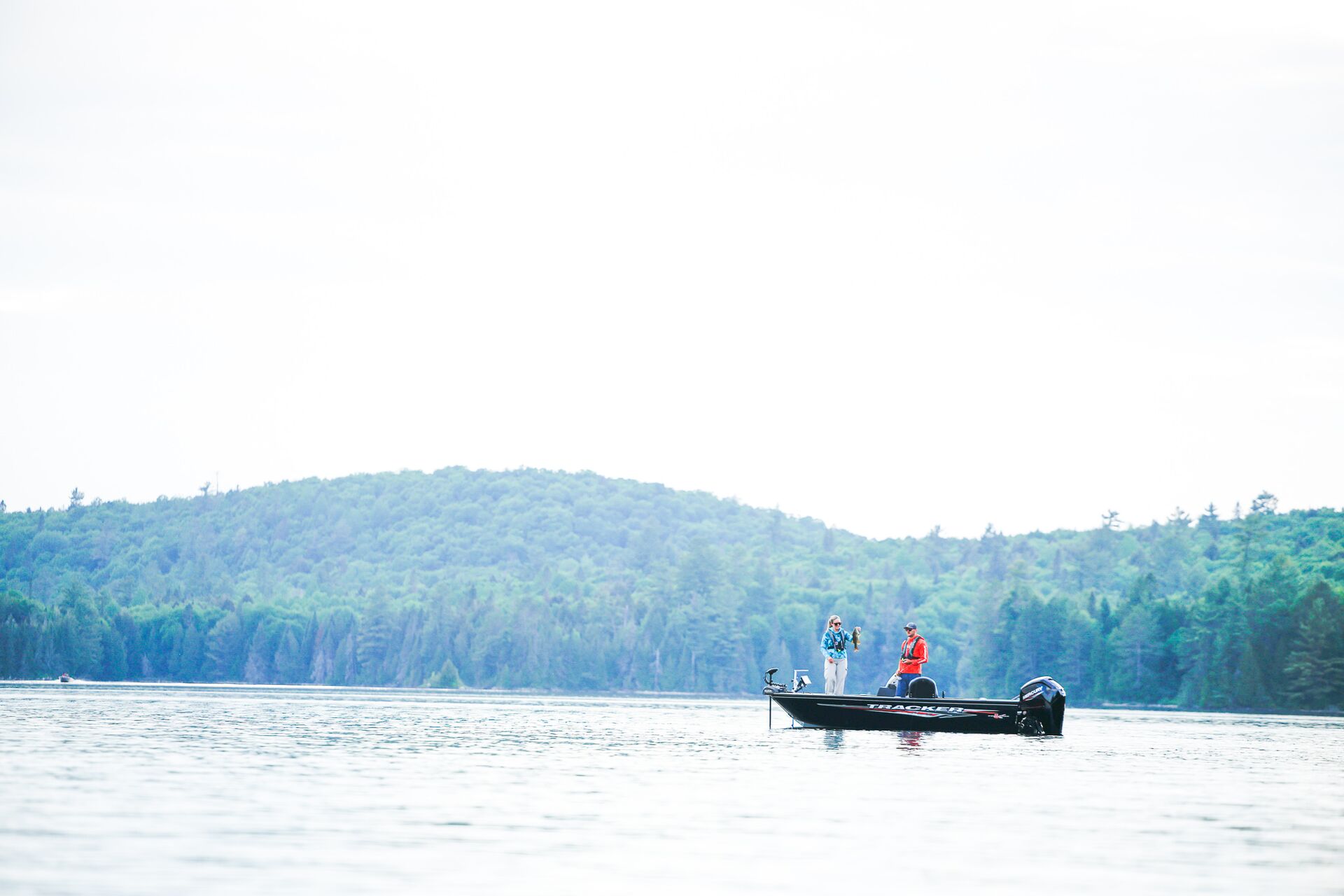 Two people on fishing boat in the distance, Labor Day boating concept. 