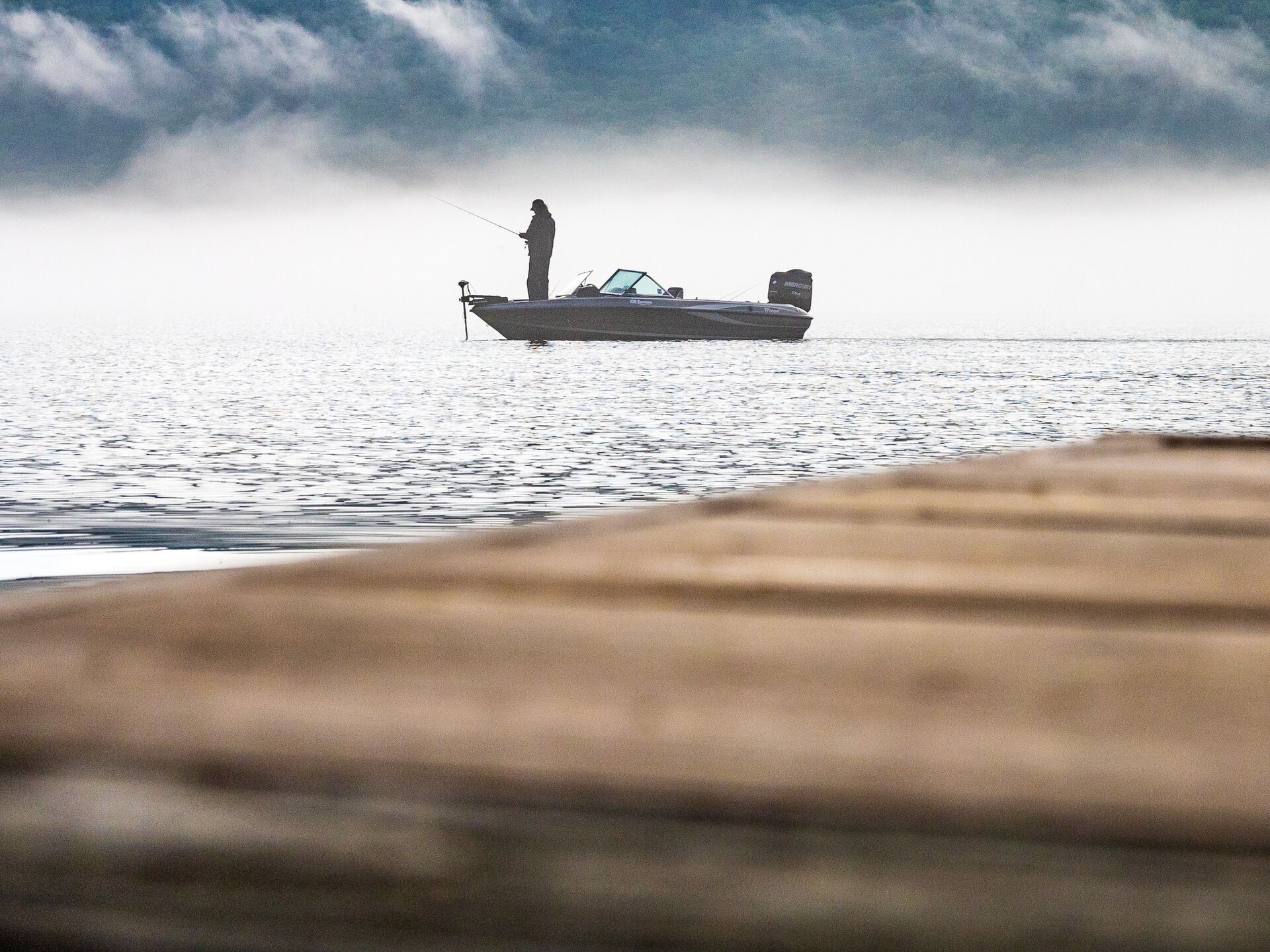 View from dock of an angler on an anchored fishing boat.