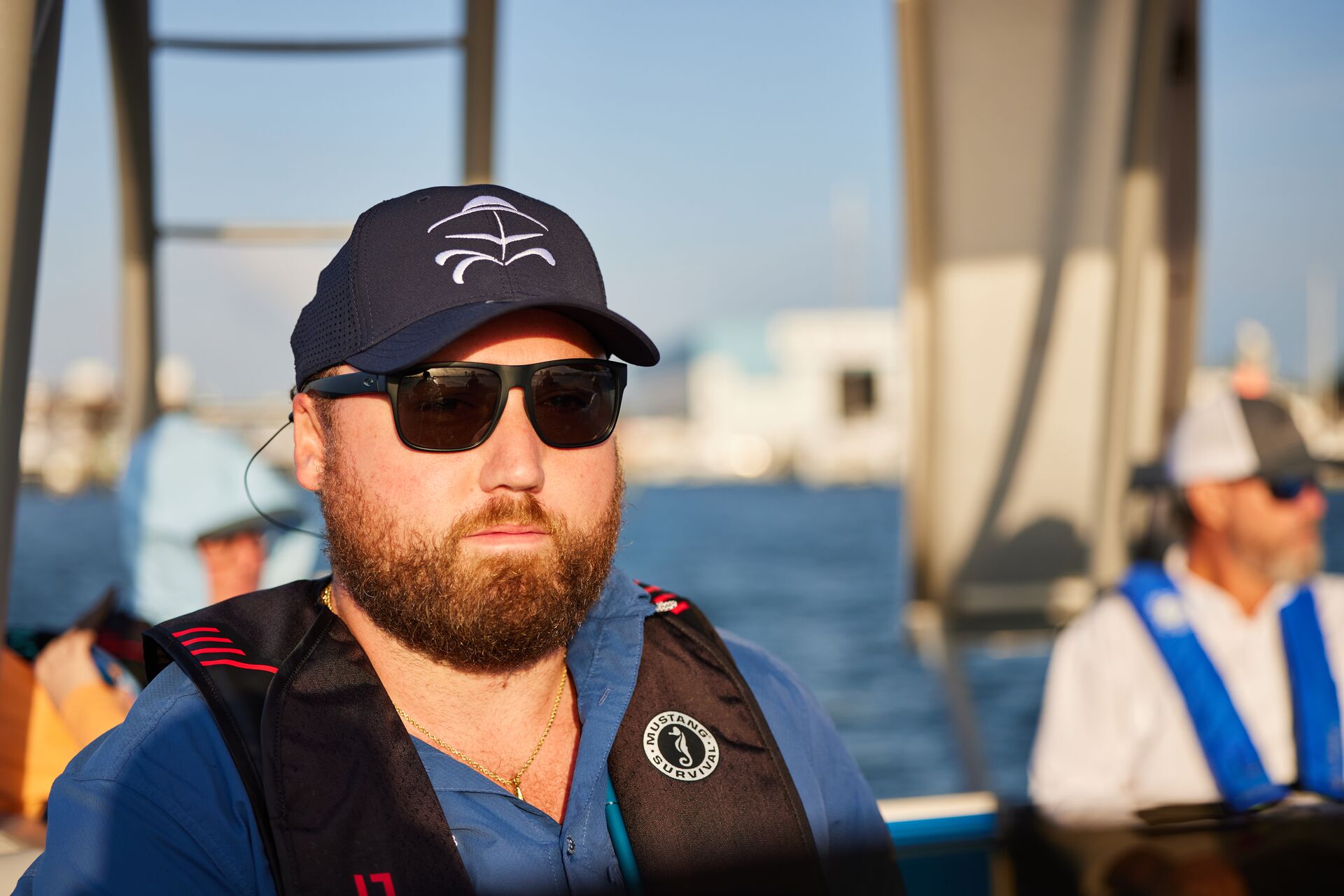 Close-up of man in life vest and sunglasses with others in background.