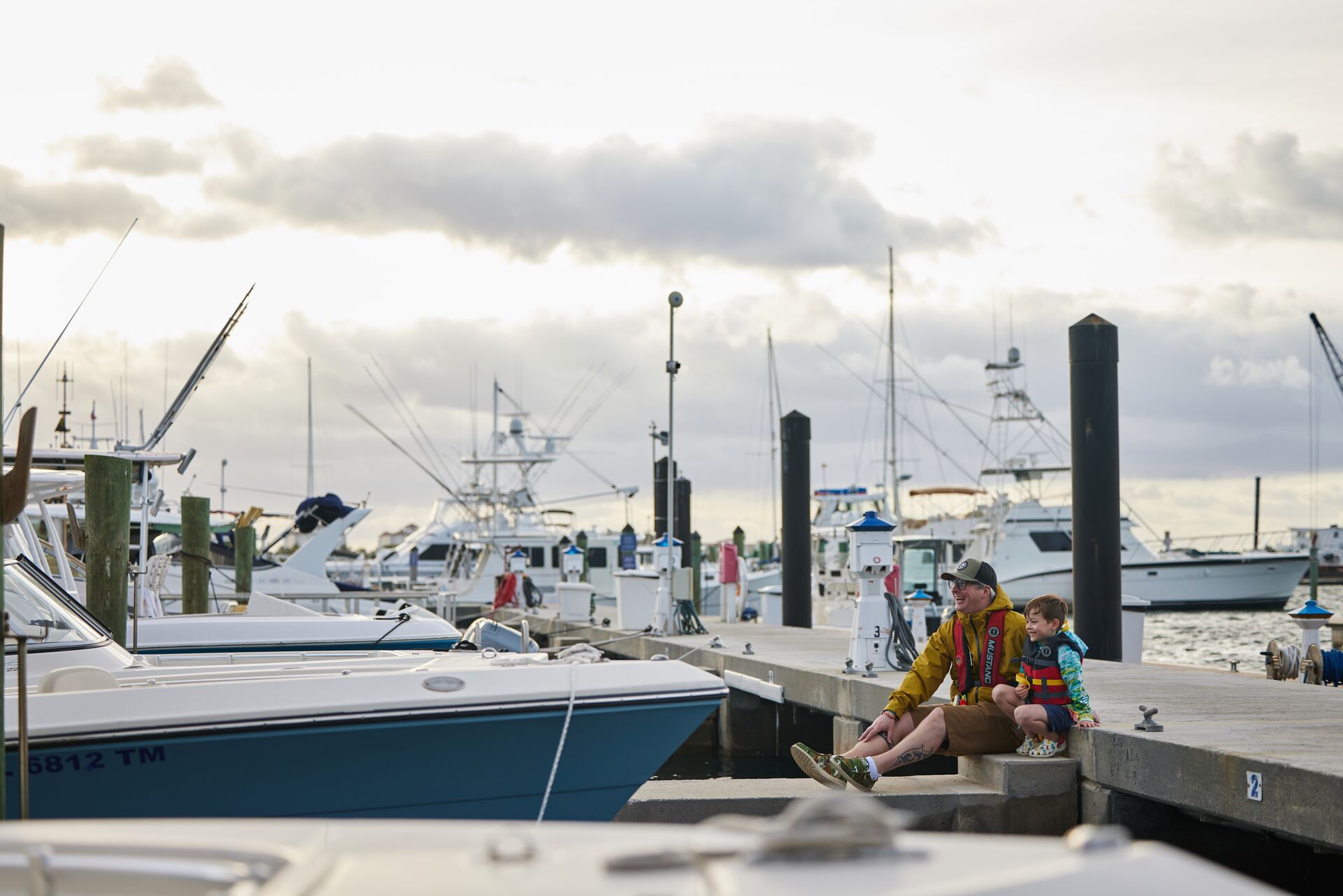 Man and boy in life jackets sit on dock, understand maritime signal flags concept. 