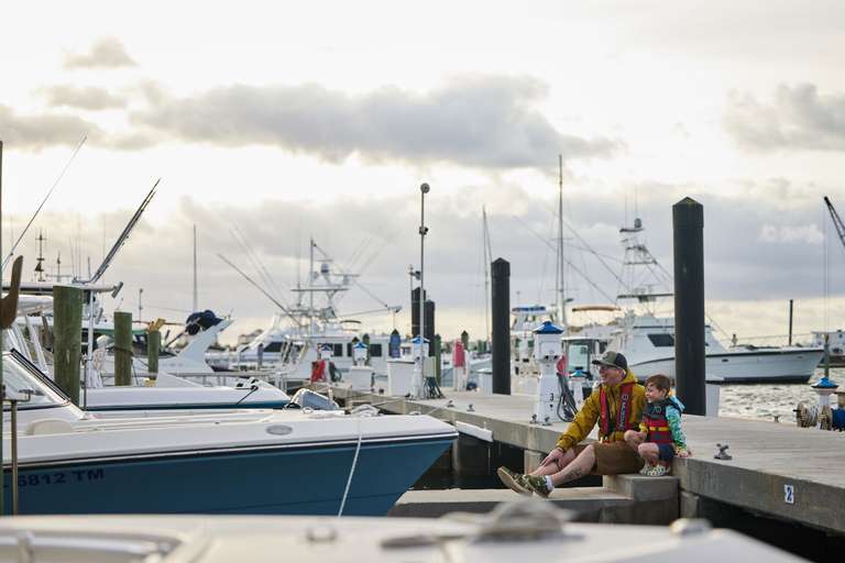 Man and boy in life jackets sit on dock, understand maritime signal flags concept. 