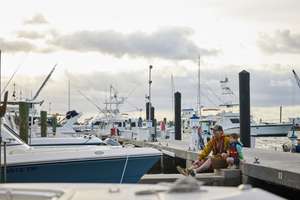 Man and boy in life jackets sit on dock, understand maritime signal flags concept.