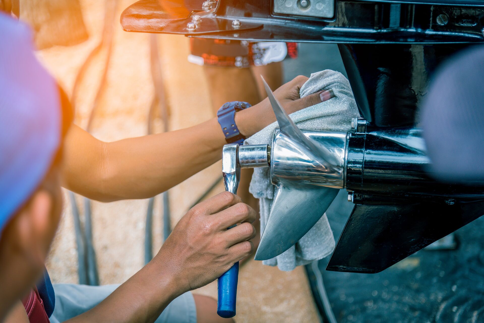 Close-up of person using tool on boat propeller, boat maintenance concept. 