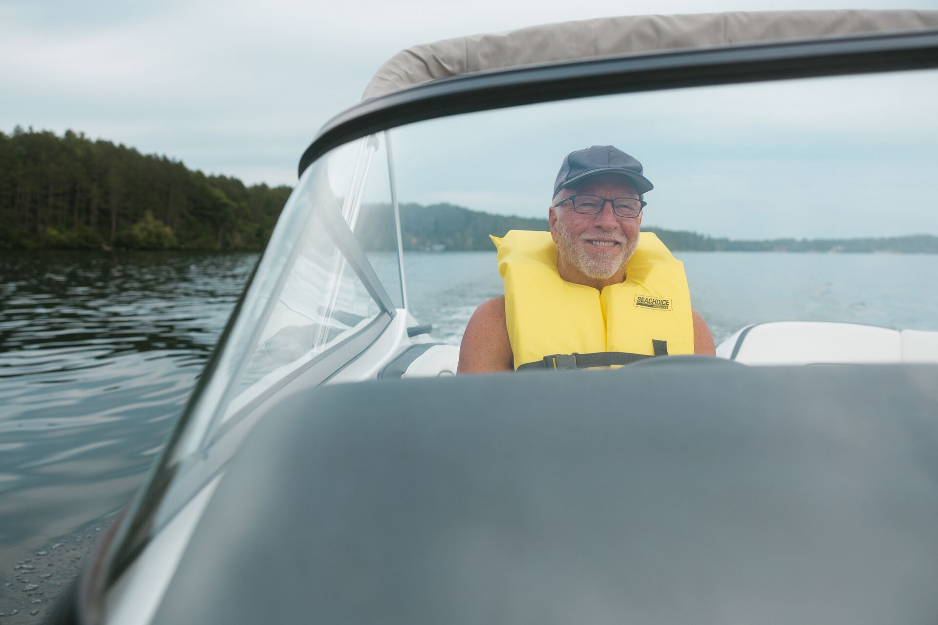 Man wears yellow life vest and smiles in boat, get boat Insurance concept. 