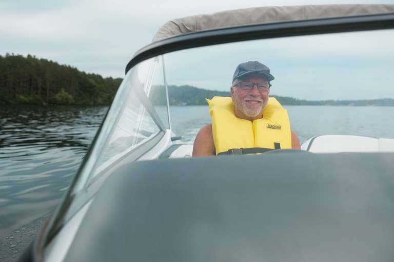Man wears yellow life vest and smiles in boat, get boat Insurance concept. 
