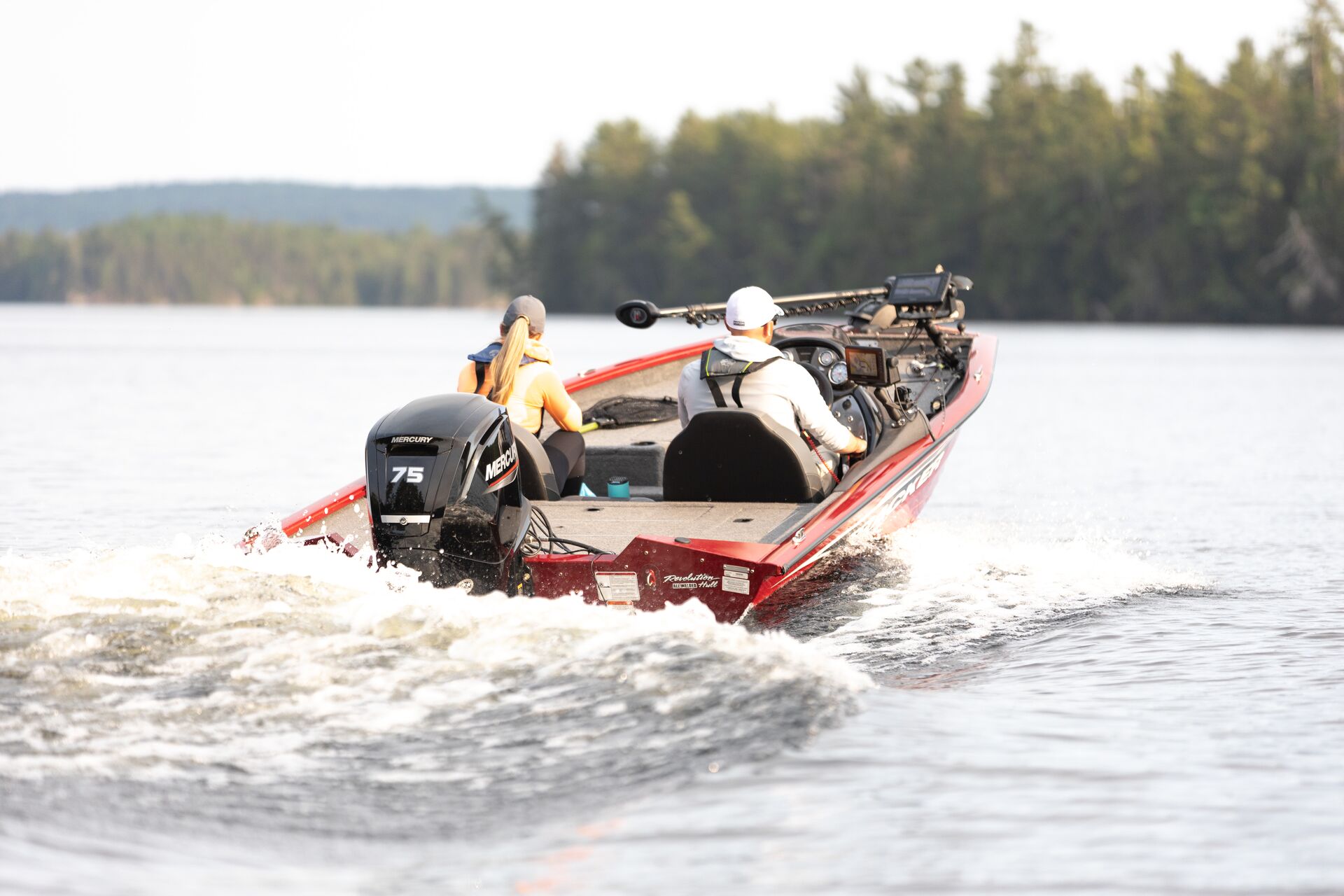 Two people in red fishing boat on the water. 
