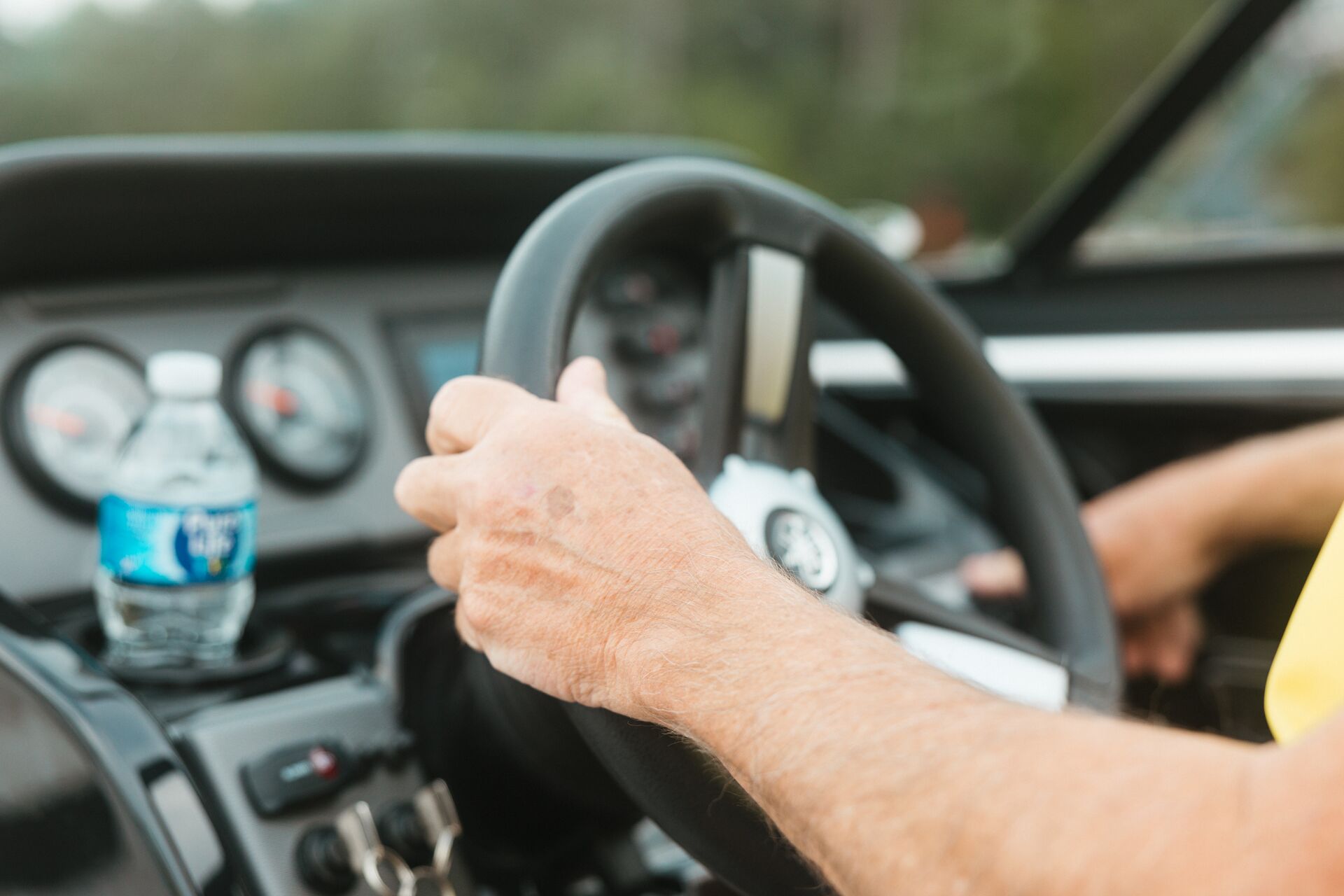 Close-up of hands on the steering wheel on a boat.