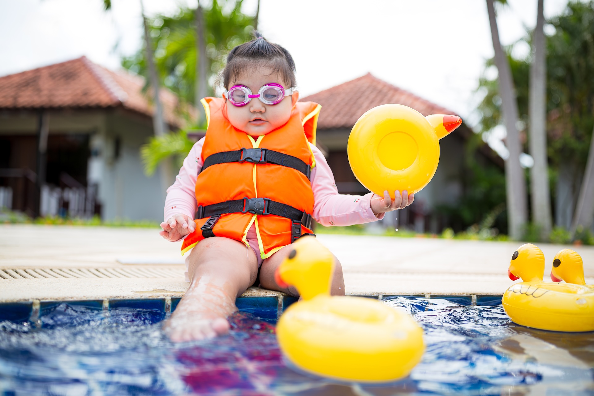 Infant in life jacket at edge of pool