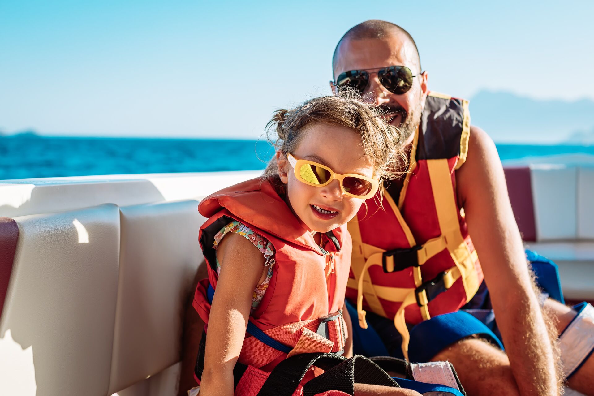 Man and child wearing life jackets on boat.