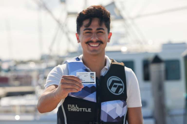 Smiling man holding a boater safety card.