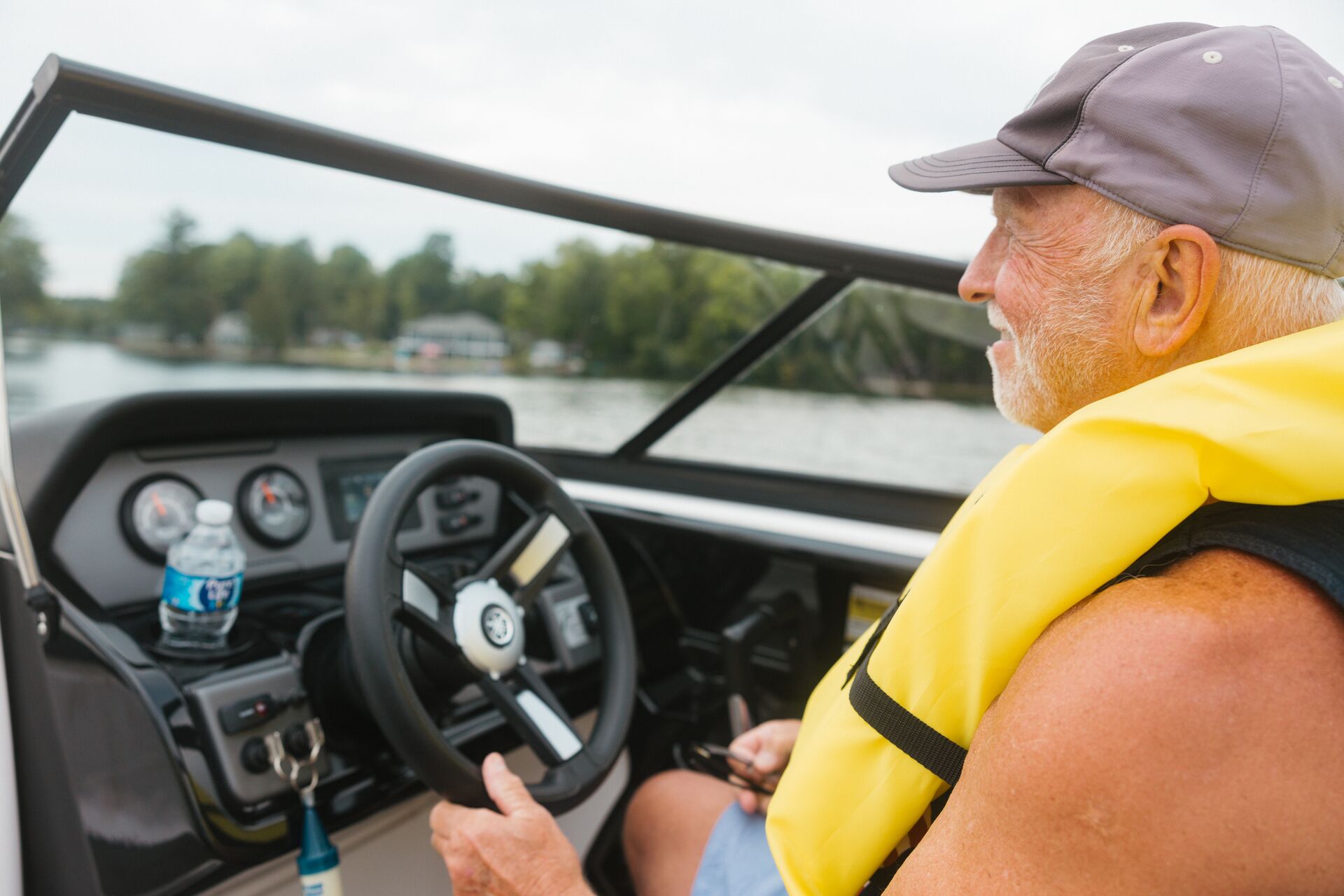 Man in yellow life vest drives boat, get your California boating license concept. 