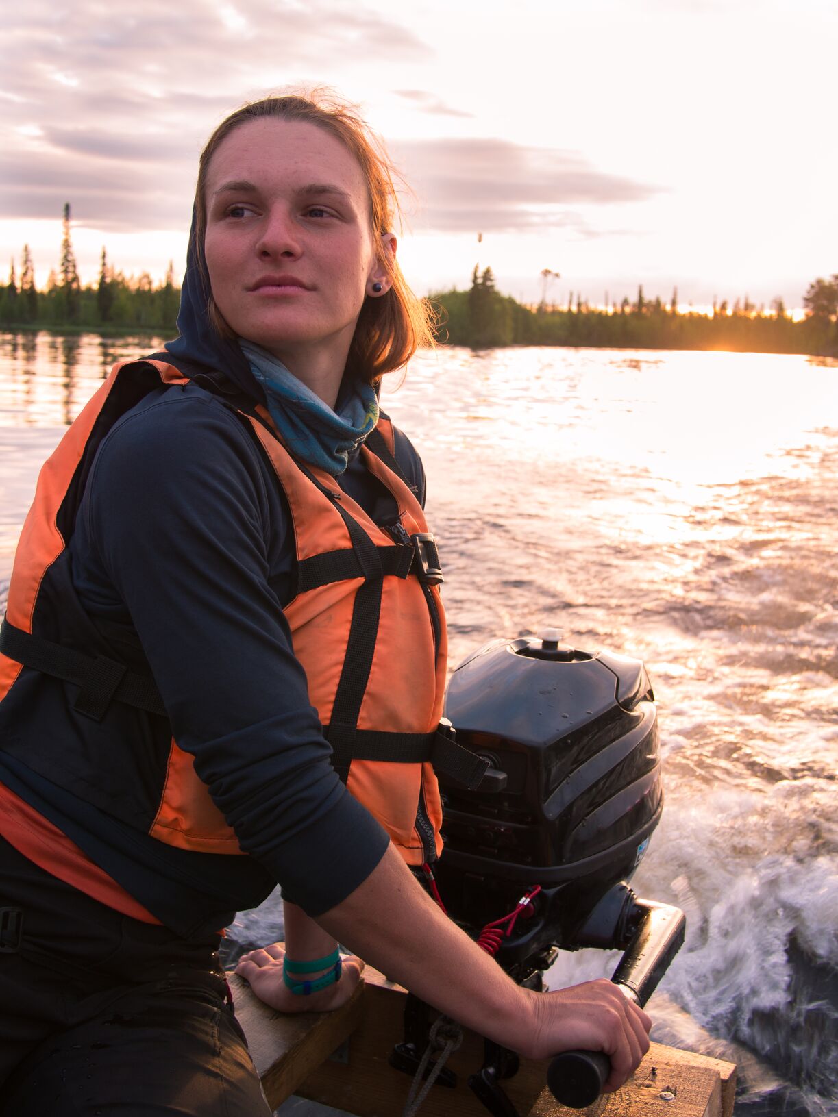 Woman in life jacket steers outboard motor on boat, get a California Boater Card concept. 