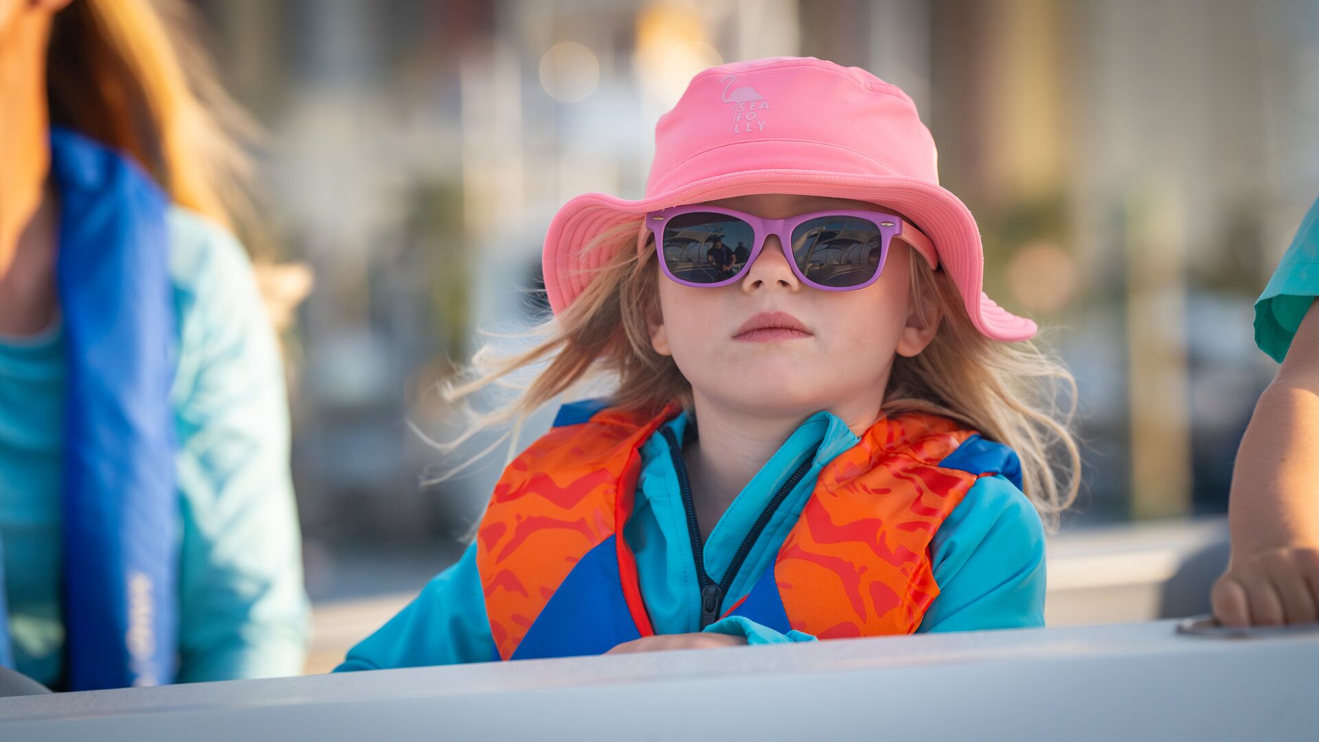 Young girl in sunglasses and life jacket on boat. 